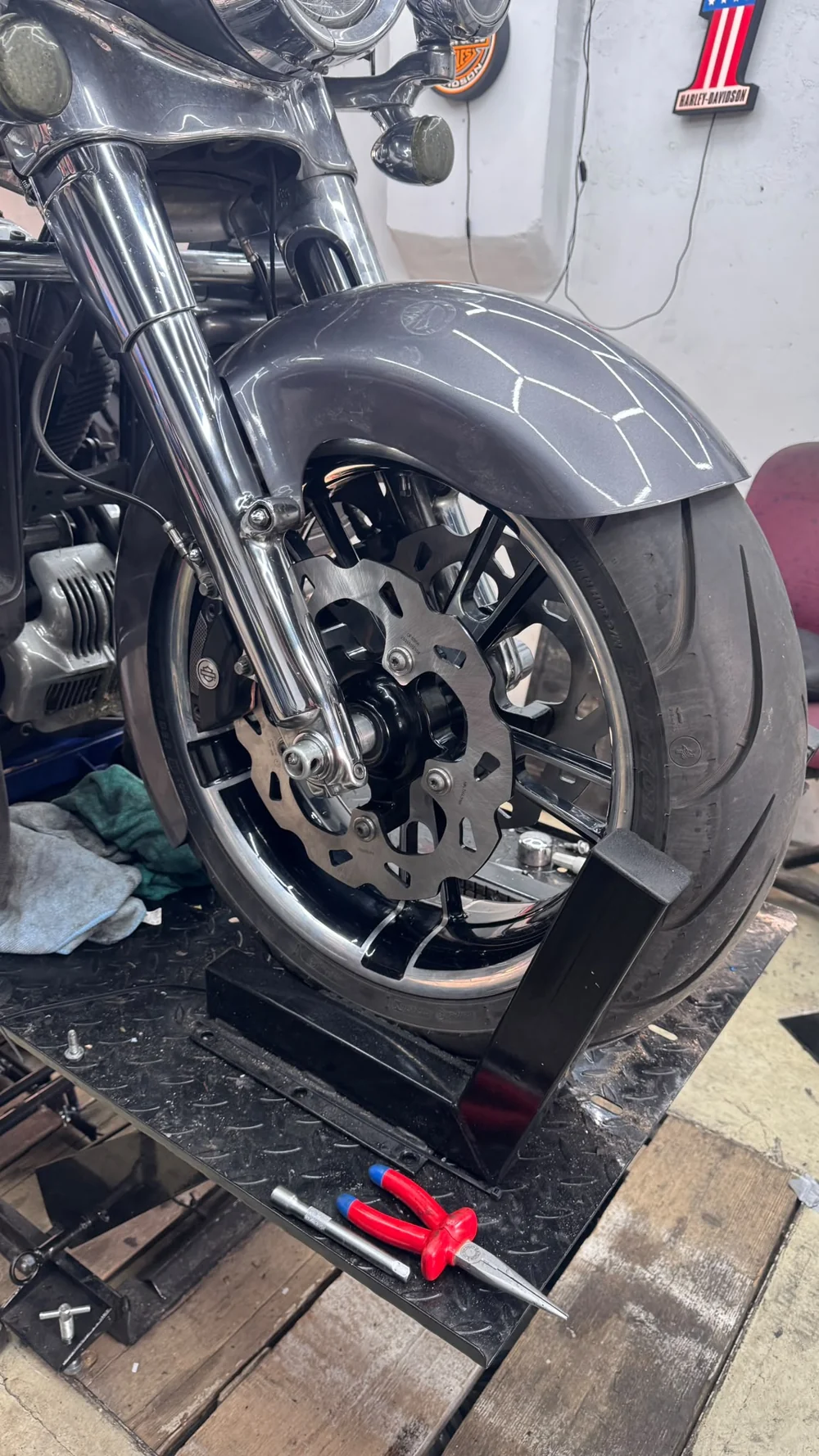 Detail van de remschijf en remklauw bij het voorwiel van een Harley-Davidson op de werkbrug