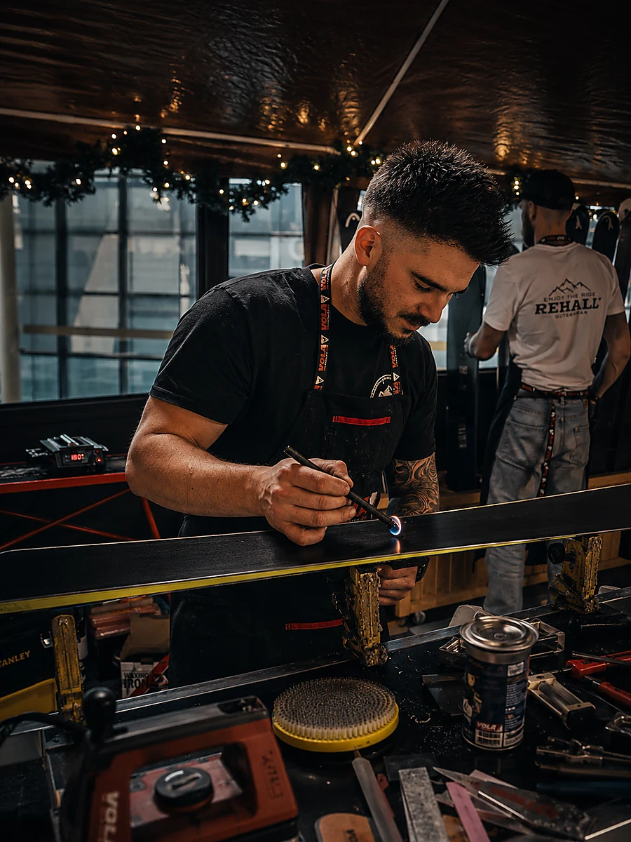 Close-up van de hand met brandende reparatiekaars boven het skibelag